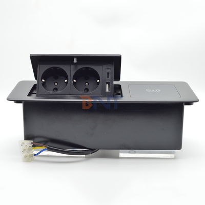 Mesa de escritorio en la que se encuentran enchufes ocultos de carga, caja de conexión múltiple, toma de corriente con carga inalámbrica